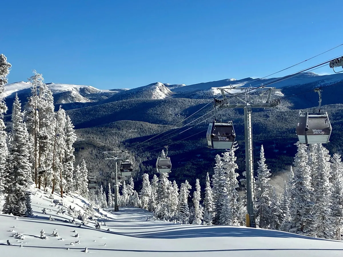 A classic ski lift glides above snow-covered slopes, surrounded by pine trees and rugged mountains. The setting is alive with winter sports possibilities, from skiing and snowboarding to scenic snowshoeing, and the mood is adventurous and exhilarating.