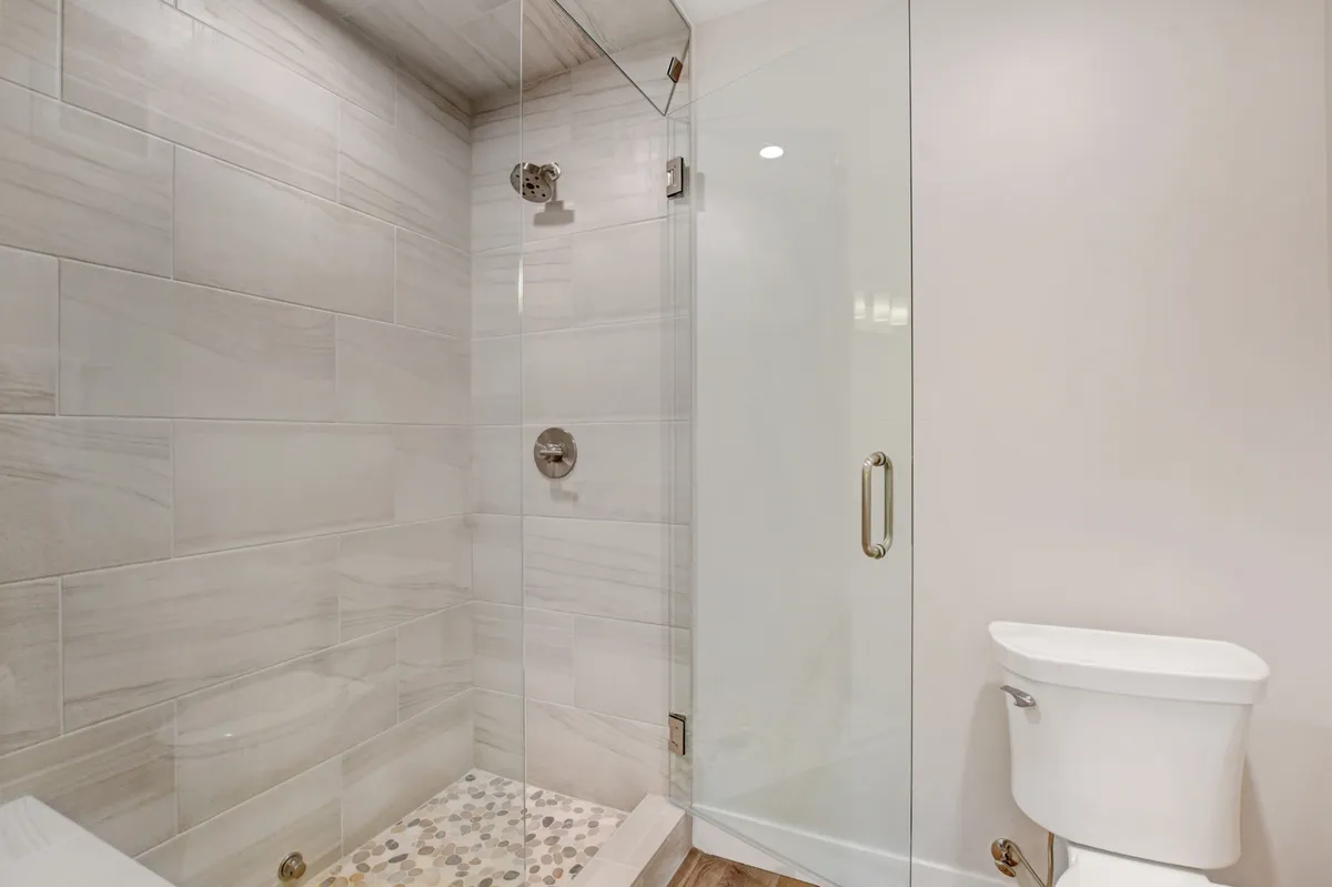 A serene bathroom featuring a glass-enclosed shower, textured tiles, and modern fixtures. The space is designed for refreshing and rejuvenating routines, evoking a spa-like atmosphere.