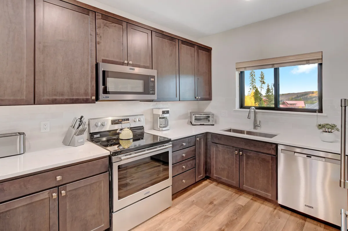 A well-appointed kitchen with modern appliances, dark cabinetry, ample counter space, and a large window that bathes the room in light. The space invites cooking, entertaining, and easy meal preparation for families.