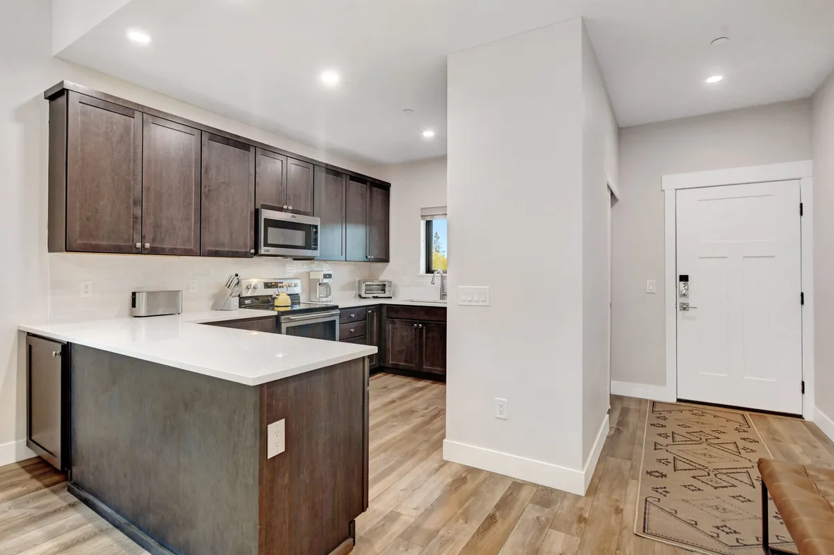 A modern kitchen with a central island, dark wood cabinets, state-of-the-art appliances, and plenty of counter space. The room is bathed in light, suggesting a functional and convivial setting for meal preparation and casual conversation.